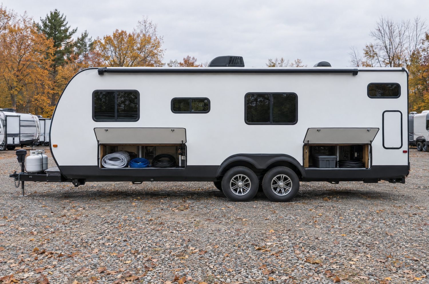 A travel trailer with its exterior bays open, wheel wells and underbelly in view